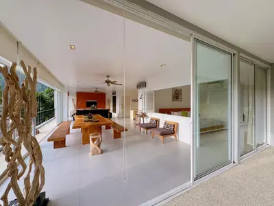 a living room with glass walls and a dining room at Peaceful The Trees Kamala Hillside in Kamala Beach