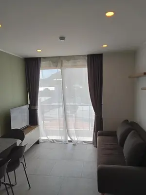 a living room with a couch and a large window at Modern Condo - 1BR T3-528 in Chalong