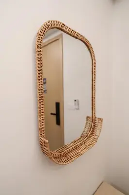 a rattan mirror hanging on a wall at Cozy 1BdR Kamala Beach Pools on the Roof in Kamala Beach