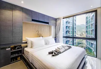 a bedroom with a large bed with a large window at Citygate resort in Kamala Beach