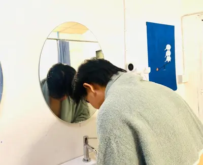 a woman looking at her reflection in a bathroom mirror at Comfort Hostel Phuket Old Town by MaTong in Phuket Town