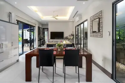 a dining room with a wooden table and chairs at Henia Villa by G Estate Phuket in Ban Saiyuan (1)