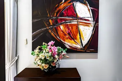 a vase with flowers on a table in front of a painting at Henia Villa by G Estate Phuket in Ban Saiyuan (1)