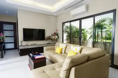 a living room with a couch and a tv at Henia Villa by G Estate Phuket in Ban Saiyuan (1)