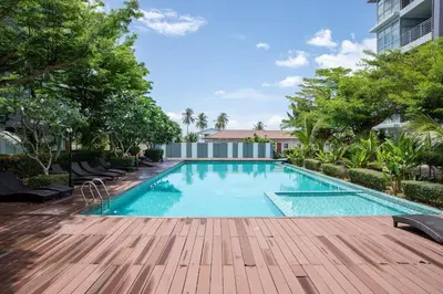 a swimming pool with a wooden deck next to a building at At Sea condo Building C, Klong Muang Beach in Ban Ko Kwang