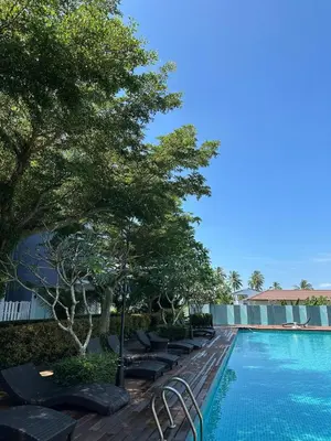 a swimming pool with lounge chairs next to a resort at At Sea condo Building C, Klong Muang Beach in Ban Ko Kwang