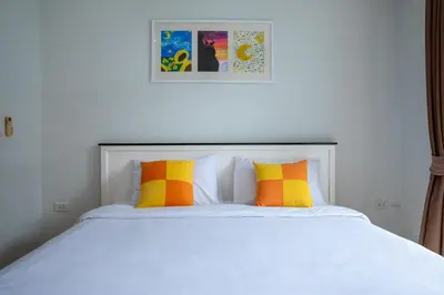 a bed with orange and yellow pillows on it at At Sea condo Building C, Klong Muang Beach in Ban Ko Kwang