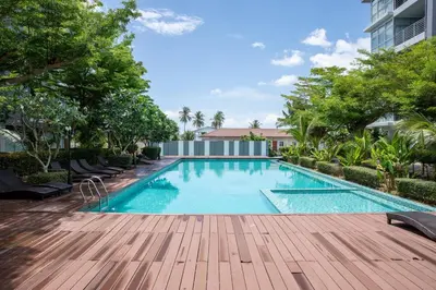 a swimming pool with a wooden deck next to a building at At Sea condo Building C, Klong Muang Beach in Ban Ko Kwang