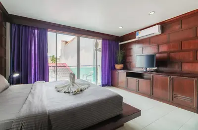 a bedroom with a large bed and a television at EBS Hostel Phuket in Karon Beach