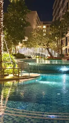 a swimming pool with a bench in a city at night at Dcondo Reef Serenity Condo 2 in Phuket Town