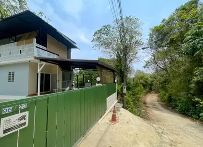 a house with a green fence next to a dirt road at Baan Sangchai Beach in Ko Bon