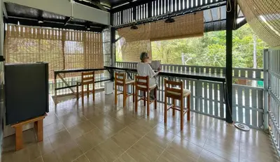 a person sitting at a table on a balcony at Baan Sangchai Beach in Ko Bon