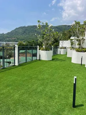 a large yard with green grass and white fences at Two-bedrooms apartments with kitchen in Phuket Town