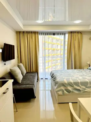 a bedroom with a bed and a couch and a window at New Apartment in 777 BEACH CONDO in Ban Mai Salae