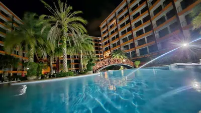 a large swimming pool with palm trees and a bridge at New Apartment in 777 BEACH CONDO in Ban Mai Salae
