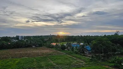 a view of a field with the sunset in the background at New Apartment in 777 BEACH CONDO in Ban Mai Salae