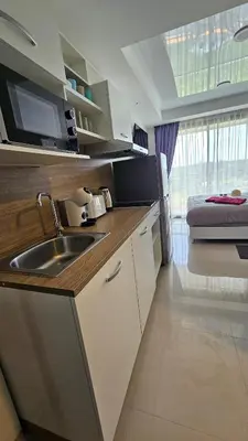 a kitchen with a sink and a bed in a room at Sunset view studio at 777 Beach Condo in Ban Mai Salae
