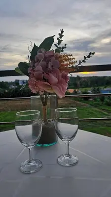 a table with two wine glasses and a vase with flowers at Sunset view studio at 777 Beach Condo in Ban Mai Salae