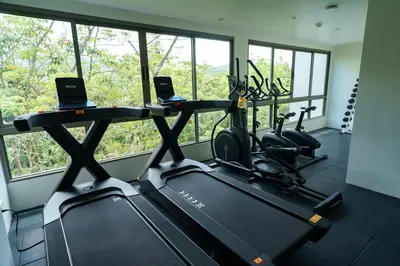 a gym with a row of treadmills and cardio machines at Kamala Beach View 1 BdR Roof Pool 500 mbps WiFi in Kamala Beach