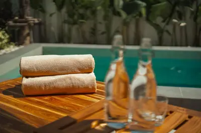 a wooden table with two bottles of alcohol on it at Staylar Pool Villas - Bangtao in Ban Pak Lak