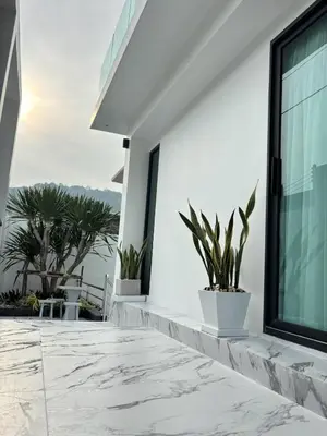a white house with plants on a balcony at Mountain breeze villa phuket in Ban Bang Khu
