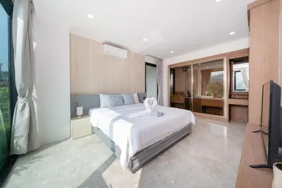 a bedroom with a white bed and a television at Luxury Pool Access 2BR Patong in Patong Beach