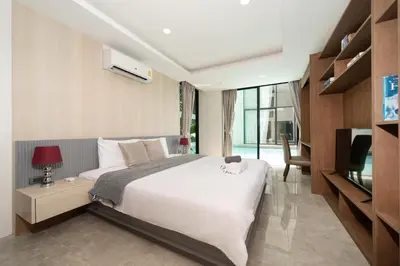 a bedroom with a large white bed and a television at Luxury Pool Access 2BR Patong in Patong Beach