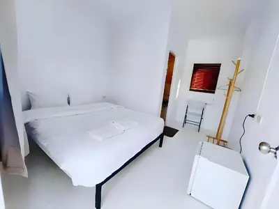 a white bedroom with a bed and a chair at XX BAO Patong Beach Phuket - เบาป่าตองบีช in Patong Beach