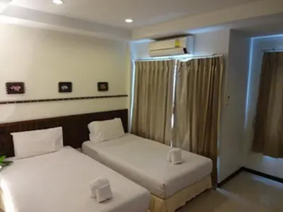 two twin beds in a room with a window at Athome Hotel Nanai 8 in Patong Beach