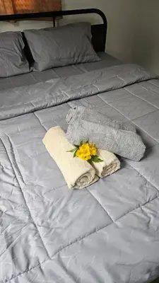 a bed with two towels and a yellow flower on it at Cozy 1-Bedroom Bungalow with Shared Pool in Rawai in Nai Harn Beach
