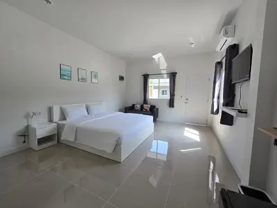 a white bedroom with a bed and a television at แวะพักสเตย์โฮสเทล Wae Phak Stay Hostel in Ban Huai Sai