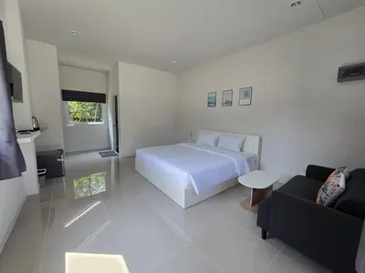 a white bedroom with a bed and a couch at แวะพักสเตย์โฮสเทล Wae Phak Stay Hostel in Ban Huai Sai