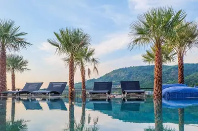 a swimming pool with palm trees and lounge chairs at Enjoy Tropical Bliss in Kamala Suite CTG L704, Top Facilities, near FantaSea & Café Del Mar Beach Club in Kamala Beach