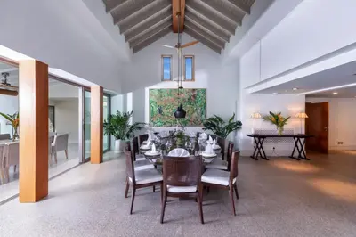 a dining room with a table and chairs and a painting at Villa Amankara in Phuket Town