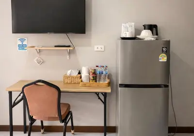a desk with a refrigerator and a table with a chair at MBB House in Thalang