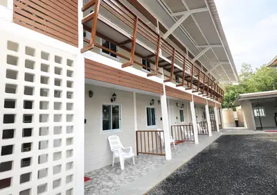 a white building with a white chair on the side at MBB House in Thalang