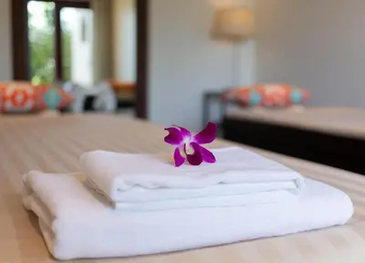 a purple flower sitting on top of three towels at Villa Talaefun - Luxury Oceanfront Fully Serviced in Kamala Beach