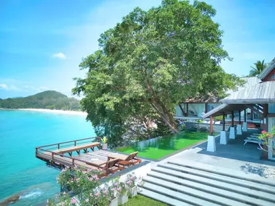 a wooden bench sitting next to a house next to the water at Villa Laemsingh 2 Oceanfront Fully Serviced in Surin Beach