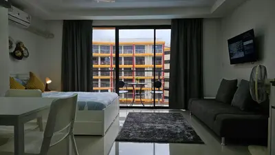 a room with a bed and a living room with a window at Cosy studio near the best beach on Phuket in Ban Mai Salae