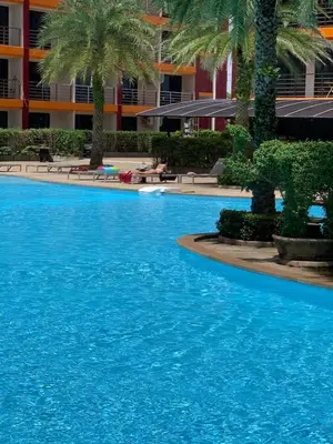 a large blue swimming pool with palm trees and a building at Cosy studio near the best beach on Phuket in Ban Mai Salae