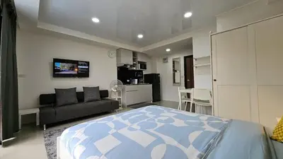 a bedroom with a bed and a couch and a kitchen at Cosy studio near the best beach on Phuket in Ban Mai Salae