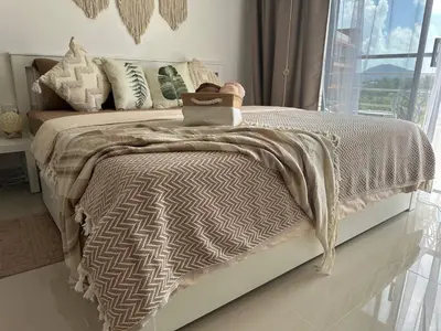 a bedroom with a bed with a blanket and a window at Kates cozy place in Mai Khao Beach
