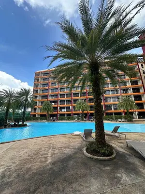 a palm tree in front of a large building at Kates cozy place in Mai Khao Beach