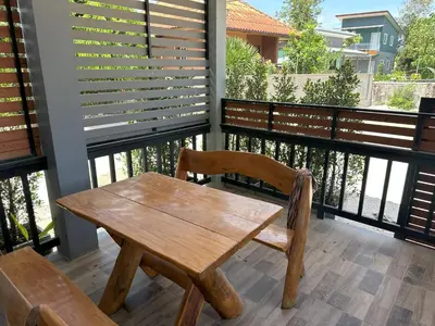 a wooden table and chairs on a balcony at Family House in Bang Tao in Ban Thalat Choeng Thale