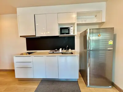 a kitchen with white cabinets and a stainless steel refrigerator at 1 bedroom Suite Seaview In Kalim in Patong Beach