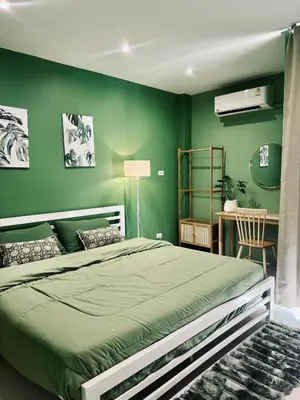 a green bedroom with a bed and a desk at Midori Rawai Hotel in Ban Saiyuan (1)