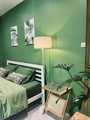 a bedroom with green walls and a bed with a table at Midori Rawai Hotel in Ban Saiyuan (1)