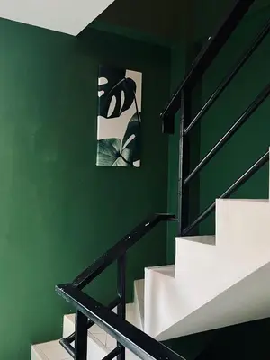 a green wall with stairs and a picture on the wall at Midori Rawai Hotel in Ban Saiyuan (1)