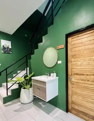 a bathroom with a sink and a mirror on a green wall at Midori Rawai Hotel in Ban Saiyuan (1)