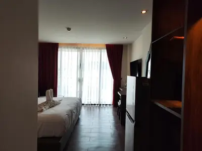 a bedroom with a bed and a large window at 7 Floor - Pool view Studio room at TBHR near Kata beach in Kata Beach